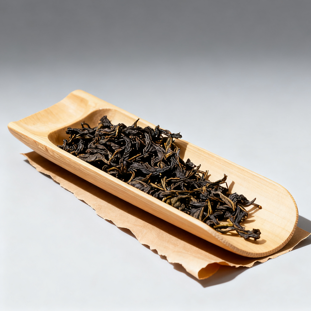 Loose black tea leaves in a bamboo tray on a parchment paper background