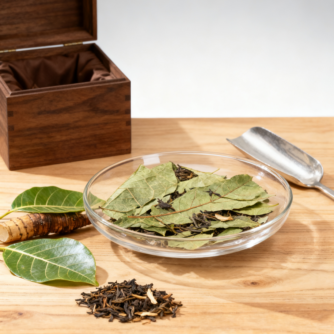 Dried tea leaves and fresh tea leaves in a glass bowl with a wooden box and tea scoop