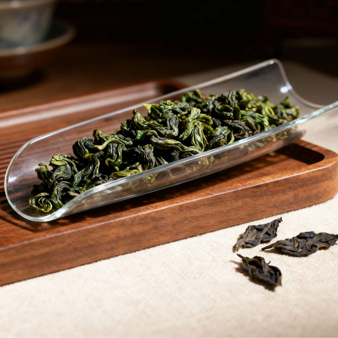 A clear glass dish filled with dry green tea leaves resting on a wooden base, creating an elegant display.